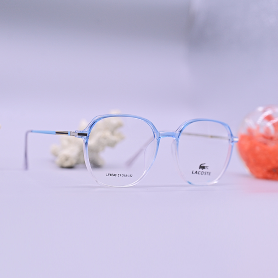 نظارة طبية من ماركة لاجوست (Lacoste) موديل 6609، إطار دائري كامل بلون أزرق سماوي شفاف مع أذرع معدنية نحيفة، متوفرة لدى عين العون.