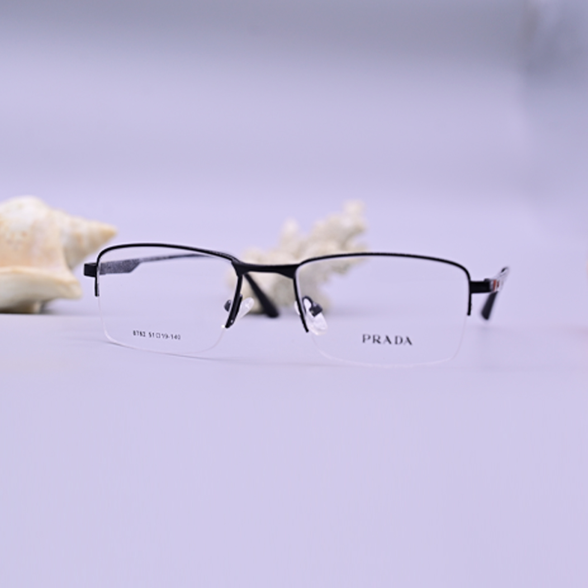 نظارة برادا طبية موديل 8782 بلون أسود فاخر، تتميز بإطار علوي كامل وتصميم شبه إطار سفلي مع شعار Prada على الأذرع، تصميم مستطيل هندسي يبرز الرقي والجدية.