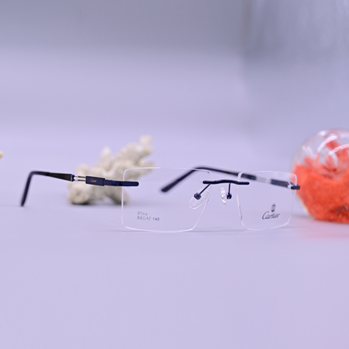 نظارة طبية فاخرة ماركة كارتير موديل 6183، تصميم بدون إطار (Rimless) بجسر وأذرع سوداء مع لمسات فضية عند المفصلات، متوفرة لدى متجر عين العون للبصريات.