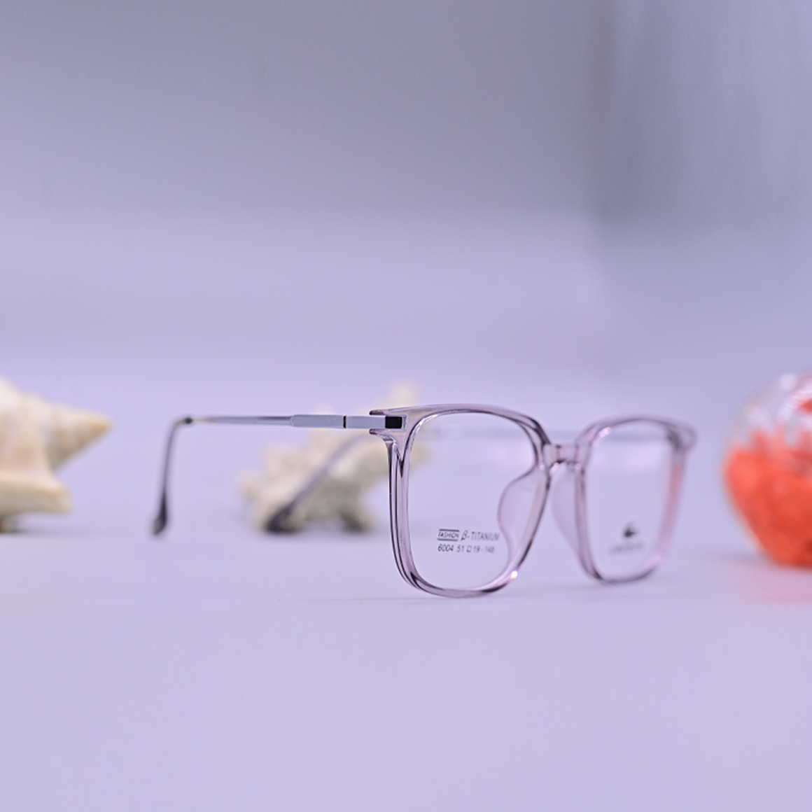 نظارة طبية ماركة لاجوست موديل 6004 بإطار دائري شفاف مائل للرمادي واللافندر وتصميم كلاسيكي مريح للنظر