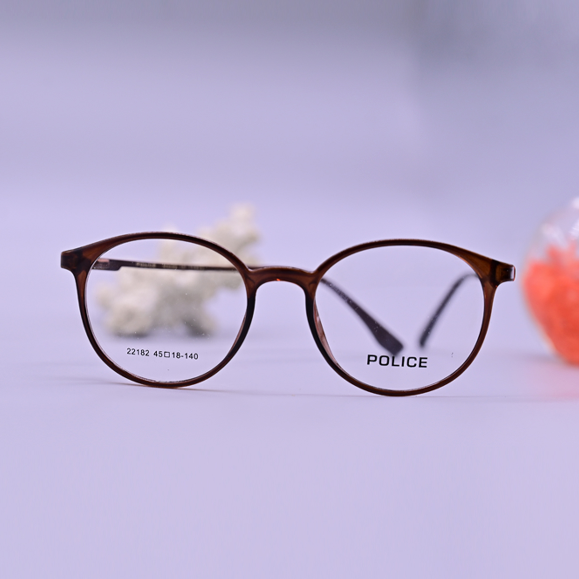 نظارة بوليس طبية موديل 22182 بإطار دائري بني من الأسيتات مع أذرع معدنية نحيفة تحمل شعار العلامة التجارية من متجر عين العون.