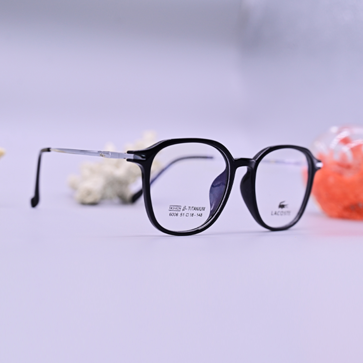 نظارة طبية من ماركة لاجوست (Lacoste) موديل 6006، إطار دائري كامل بلون أسود لامع وأذرع معدنية فضية رفيعة، متوفرة في متجر عين العون للبصريات.